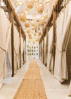 a long hallway lined with hanging lights and wicker rugs on either side of the room