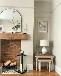 a living room with a fire place, mirror and lamp on the wall next to it