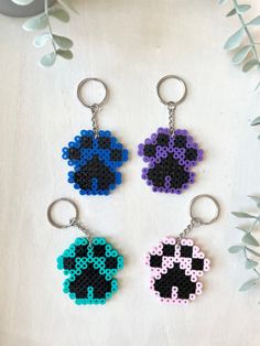 three keychains with different designs on them sitting next to each other, one in the shape of a dog's paw