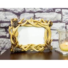 a wooden frame sitting on top of a table next to a candle and glass vase