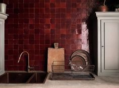 a kitchen with red tiles on the wall and a sink in front of an oven