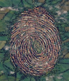 an aerial view of a village in the middle of a field with trees and clouds