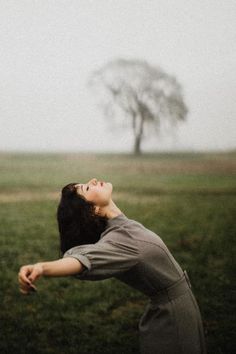 a woman standing in the grass with her eyes closed