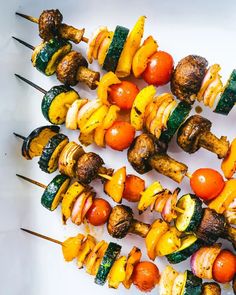 several skewers of different types of food on a white surface