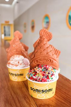 two ice cream cones with sprinkles and chocolate frosting on a table