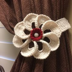 a crocheted flower is attached to the back of a brown and white curtain