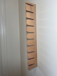 a wooden rack mounted to the side of a wall next to a white wall and door