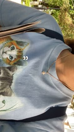 a person wearing a shirt with a cat on it's chest holding a pair of scissors