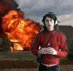 a man standing in front of a fire with headphones on and his arms crossed