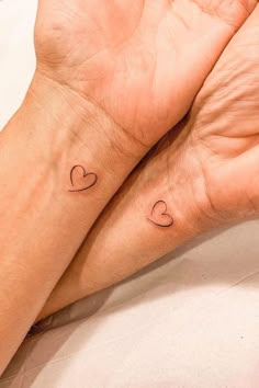 two hands holding each other with small hearts on their wrist tattoo designs for women and men