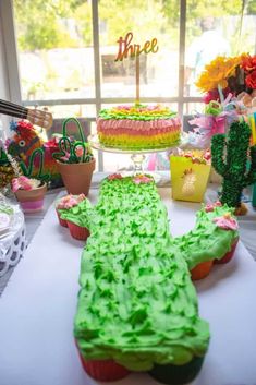 a table topped with cupcakes covered in green frosting