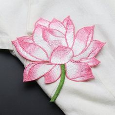 a pink and white flower embroidered onto a white shirt