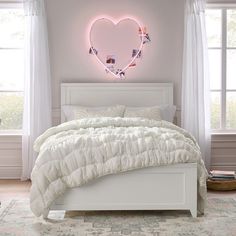 a white bed with a heart shaped neon light above it in a pink bedroom setting