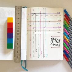 an open notebook with colored pencils next to it and a ruler on the side