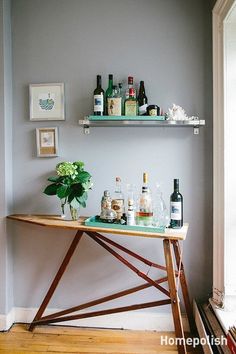 a wooden table topped with bottles and glasses next to a shelf filled with liquors