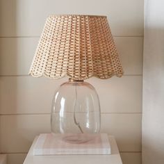 a glass lamp sitting on top of a white table next to a wall mounted clock