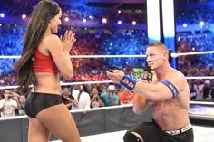 a man kneeling down next to a woman on top of a wrestling ring in front of an audience