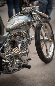 a silver motorcycle parked on top of a cement floor next to other motorcycles and people