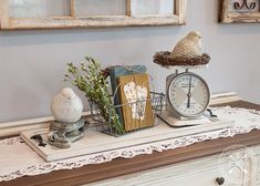 a white dresser topped with a clock, bird nest and other items on top of it