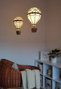 two lights are hanging from the ceiling above a wicker chair in a living room