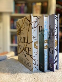 three books sitting on top of each other in front of a book shelf filled with books