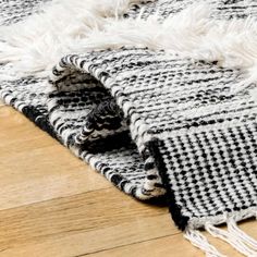 a black and white blanket laying on top of a wooden floor