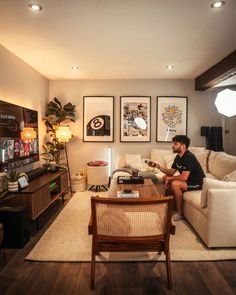 a man sitting on top of a couch in a living room next to a table