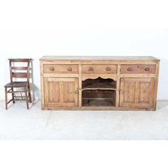 an old wooden sideboard with two chairs next to it