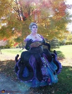 a woman dressed in costume sitting on top of a black chair next to a tree