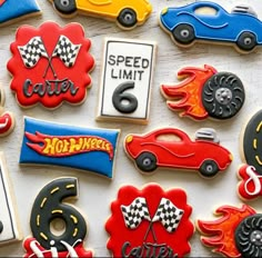 decorated cookies with cars and numbers are displayed on a white tablecloth, which is laid out in the shape of race cars