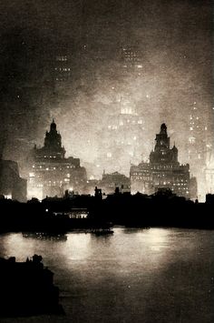 the city skyline is lit up at night in black and white, as seen from across the river