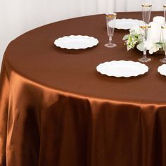 the table is set with wine glasses, plates and napkins on top of it