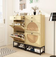 a wooden cabinet with shoes on it in a room next to a lamp and rug