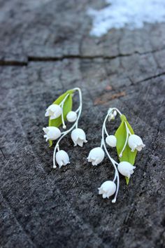 small white flowers are attached to silver earwires on a piece of wood with water droplets