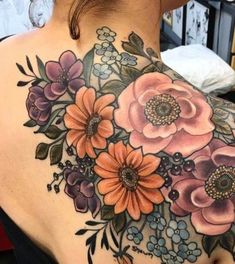 the back of a woman's shoulder with flowers and leaves tattoo on her chest