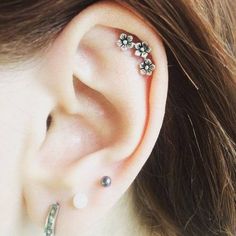 a close up of a person's ear with piercings on top of it