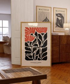 two framed art prints on the wall in a room with wood floors and wooden furniture