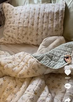 an unmade bed with two pillows and a blanket on it's side, next to a phone