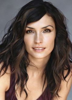 a close up of a woman with long hair and brown eyeshadow wearing a black top