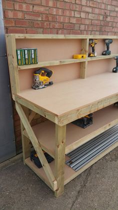 a workbench with tools on it sitting in front of a brick wall