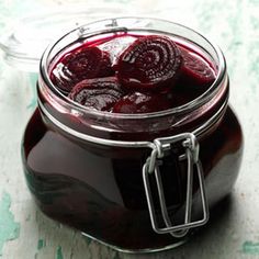 a jar filled with red liquid sitting on top of a table next to a knife