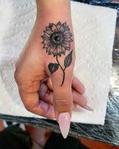 a woman's hand with a sunflower tattoo on it