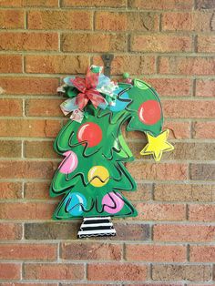 Grab the crooked Christmas tree to add to you holiday decorations! What you will receive in your order: - 1 wood door hanger cut with my jigsaw and painted with a hand tied bow attached if you choose. *Ribbon design may vary depending on stock but will match the door hanger. - 3 felt circle pads for you to stick to the back of your door hanger where it touches your door.   About your item: - This door hanger is cut from ¼" BC Exterior Plywood. - Sanded, hand painted and sealed on both sides with Elf Door Hanger, Porch Sign Christmas, Christmas Tree Door Hanger, Tree Door Hanger, Winter Door Hanger, Christmas Tree Door, Holiday Door Decor, Door Decor Christmas, Tree Door