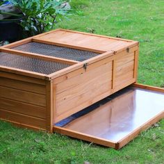 a large wooden box sitting on top of a grass covered field next to a bush