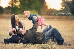 a man and woman laying on the ground with a baby in their lap, holding up a toddler