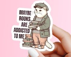 a person holding up a sticker with a cat on it's back and the words maybe books are added to me