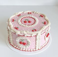 a pink cake decorated with cherries and white icing