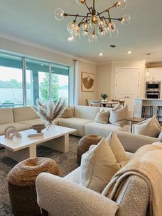 a living room filled with lots of furniture and a chandelier hanging from the ceiling