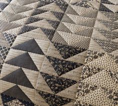 an up close view of a quilt with black and white designs on it, including triangles