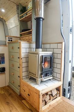 the interior of a small camper with wood burning stove and storage area in it